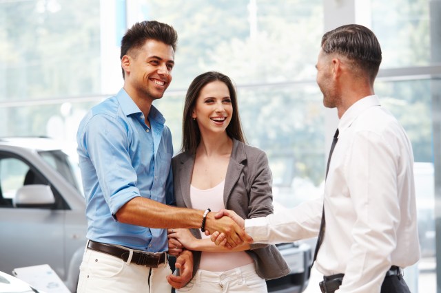 Couple shaking hands with car dealer on extended warranty