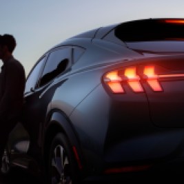 Man leaning against car at dusk