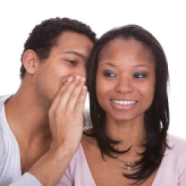 Man whispering in woman’s ear