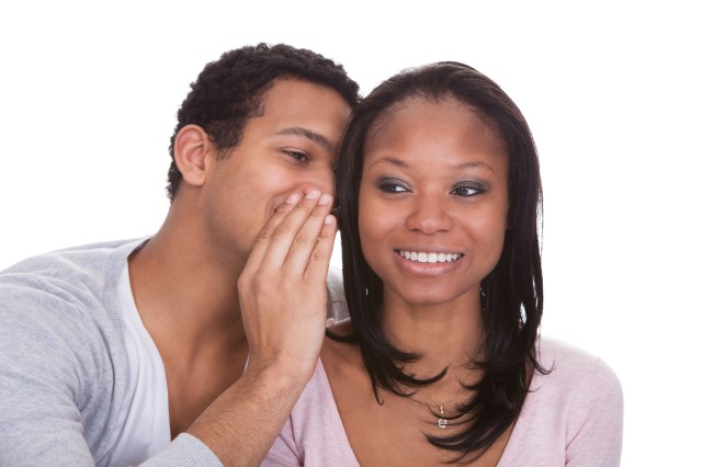 Man whispering in woman’s ear