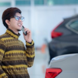 Man car buying on phone in showroom